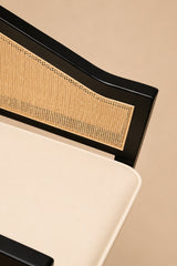 Levanto Dining Chair in black wood with natural rattan backrest and cream upholstered seat in a luxury dining interior.