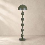 Olive green sculptural floor lamp on warm beige plaster and limestone background