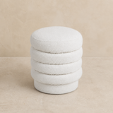 Ambasciata ivory bouclé ottoman on a warm beige studio background