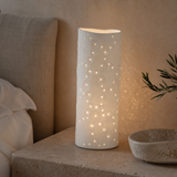 Ari white porcelain lamp softly illuminated in a boutique bedroom