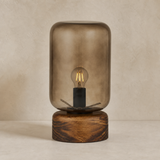 Belize lamp with smoked glass cloche and wooden base in a warm beige studio