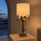 Bermuda antique brass palm table lamp glowing at blue hour