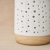 Close-up of the perforated porcelain and natural wood base of the Bolla Lamp