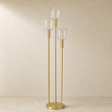 Bruno brass and clear glass floor lamp against a warm beige studio wall