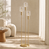 Bruno three-light brass floor lamp in a sunlit European reading nook
