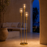 Bruno brass and glass floor lamp illuminated in a Mediterranean lounge at blue hour