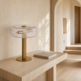 Deluca gold metal and ribbed glass lamp on a travertine console