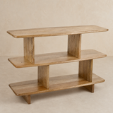 Lucia White — natural wood three-tier shelving unit on warm beige Elara studio floor