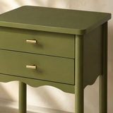 Close-up of the olive-green finish, brass pulls and scalloped apron