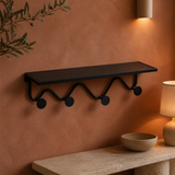 Oriel black metal wall shelf and four-hook rack in a warm evening interior