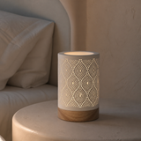 Palm perforated white cylinder lamp glowing in a refined bedroom