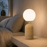 Palma travertine globe table lamp glowing in a refined bedroom
