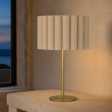 Sombra Gold Natural table lamp on a stone console at dusk