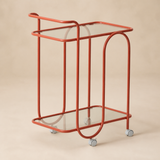 Trinità coral metal and glass trolley in a warm beige studio