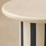 Close-up of the Tyra table rounded cream top and striped pedestal