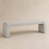 Veneziana continuous waterfall bench in fine stone-ivory woven upholstery with exactly two broad end-panel supports, Elara beige studio view