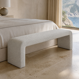 Veneziana continuous waterfall bench in fine stone-ivory woven upholstery with exactly two broad end-panel supports, bedroom lifestyle angle