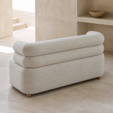 Rear elevated view of Vernazza compact sofa showing exactly two continuous stacked rounded bolster rails, monolithic upholstered base and low wooden ball feet