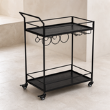 Elevated angle of the Walker all-black bar cart with exactly two tray shelves, four posts, four casters, bottle rings and stemware rack