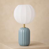 Wilton blue-grey fluted ceramic lamp with one short brass neck and flattened spherical ribbed white shade in a warm beige studio