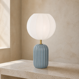 Wilton blue-grey fluted ceramic table lamp with brushed brass neck and large ribbed white balloon shade in a premium Mediterranean interior