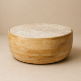 Zahara circular marble and honey mango wood drum coffee table with convex block body in a warm beige studio